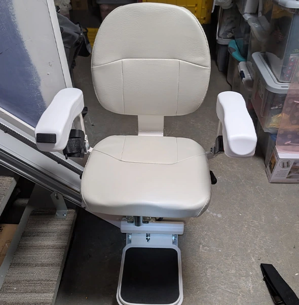White stair lift chair with folded footrest, ready for use.