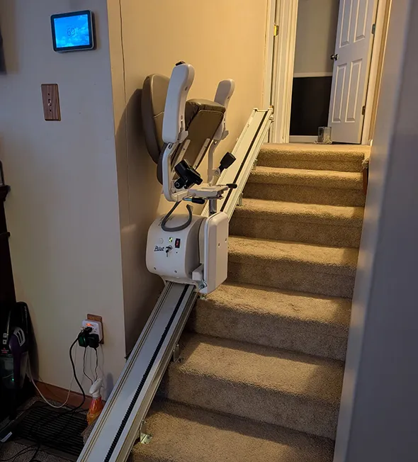 Stair lift chair installed on a carpeted staircase in a home.