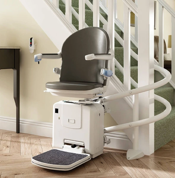 White stairlift with gray seat and armrests next to a staircase